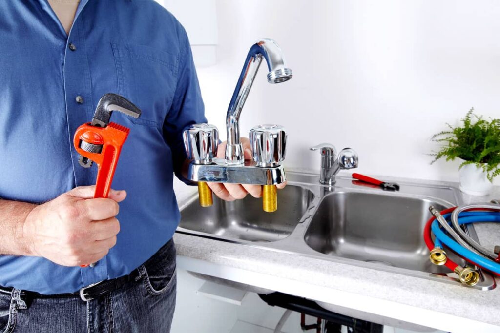 A man in blue is presenting his tools and the faucet