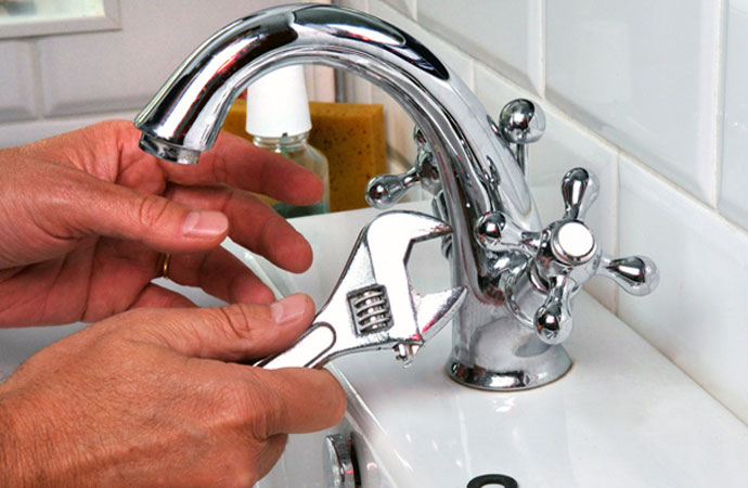 A plumber is installing a faucet using his tools