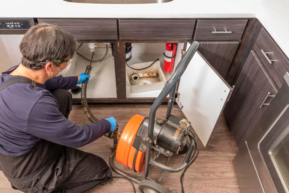 A plumber is using a drain snake