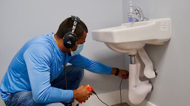 A workeris wearing ear protection while performing water leak repair