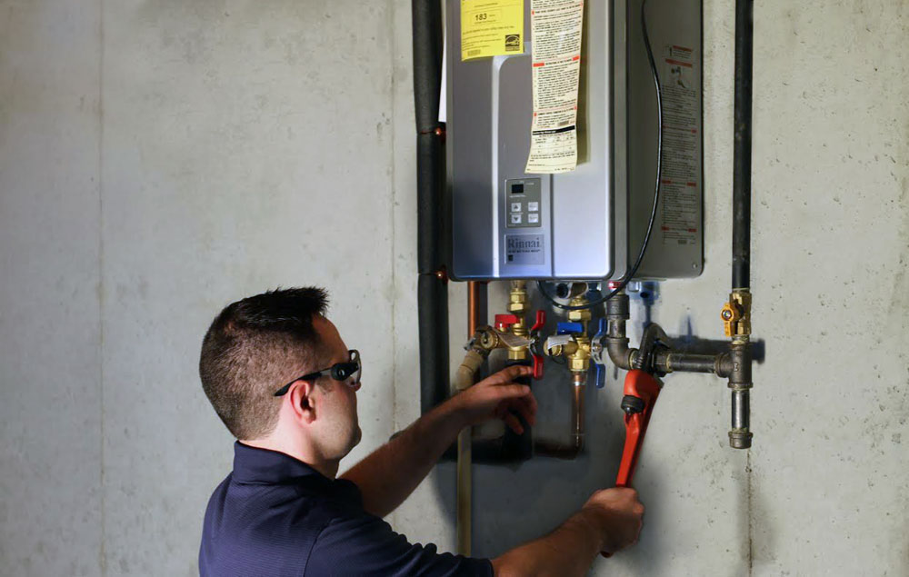 A male worker wearing eye protection is checking the water tank