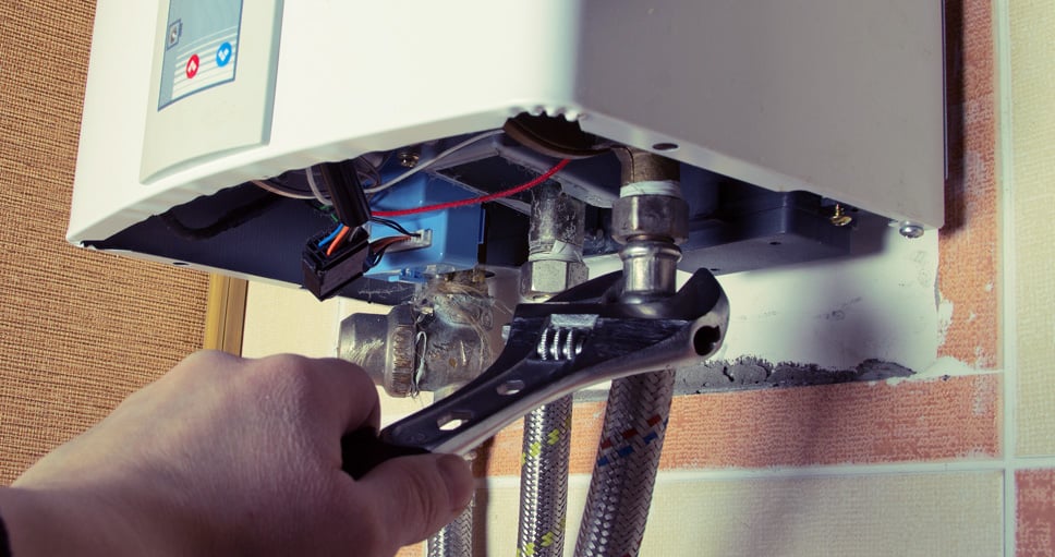 A worker's hand is repairing the Water heater using tools