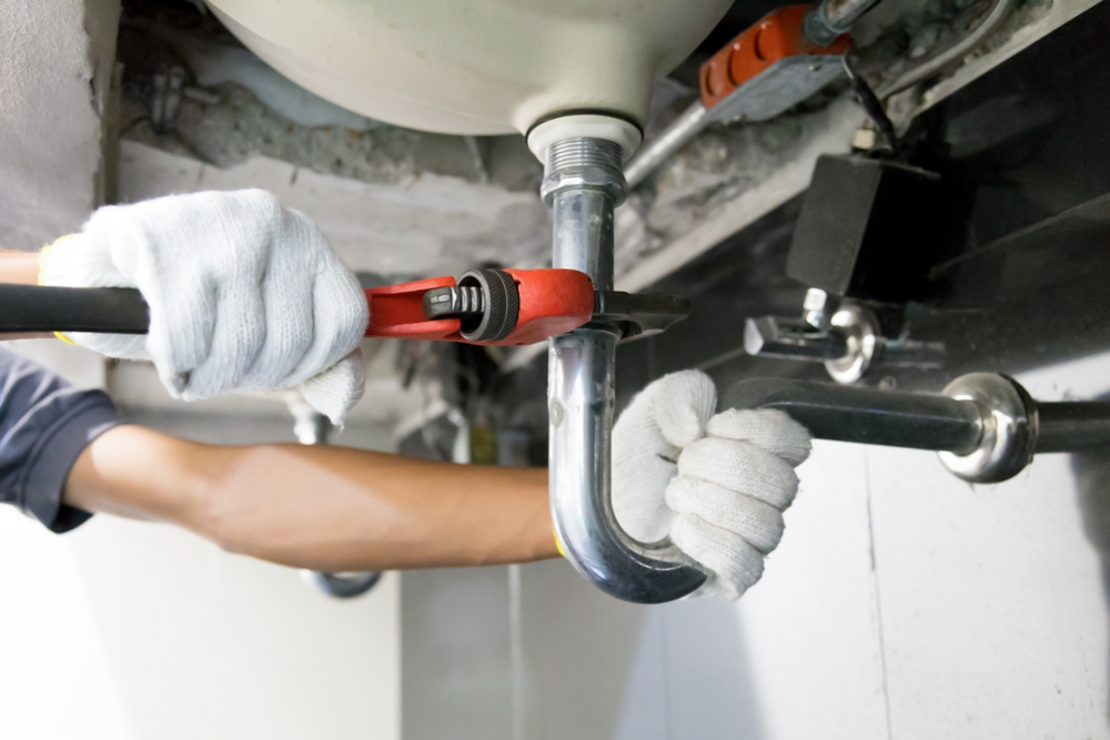 Plumber Using A Wrench To Repair A Water Pipe